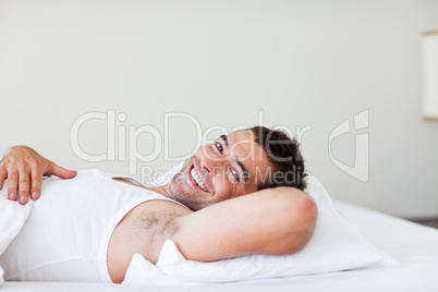 Handsome man lying in bed smiling
