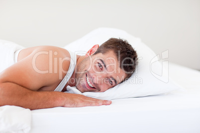 Handsome man lying in bed smiling