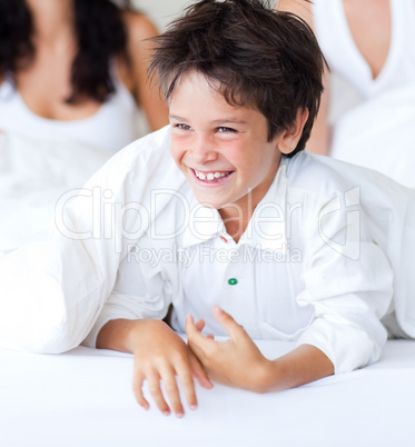 Smiling son having fun with his parents in bed