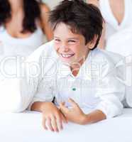Smiling son having fun with his parents in bed