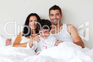 Portrait of a son with thumbs up and his parents in bed
