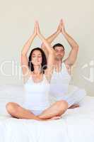 Couple doing exercises on bed with closed eyes