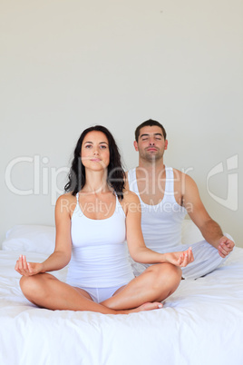 Couple in meditation pose on bed