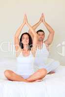 Couple sitting on bed practicing yoga