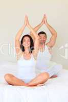 Couple sitting on bed in meditation pose