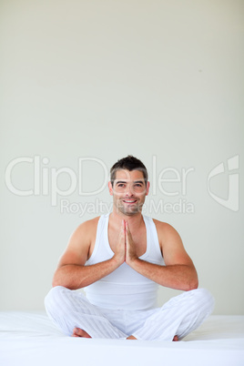 Young man meditating in bed with copy-space