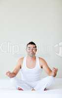 Smiling young man doing yoga in bed