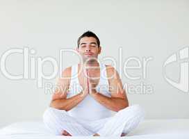 Young man practicing yoga in bed