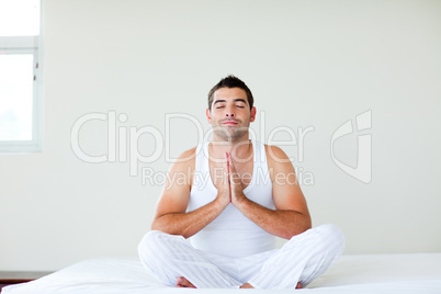 Man sitting on bed meditating with clossed eyes