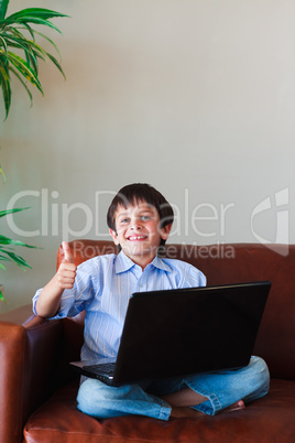 Kid using his laptop with thumb up