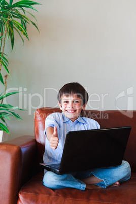 Kid using his laptop with thumb up