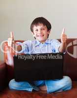 Child playing with his laptop with thumbs up