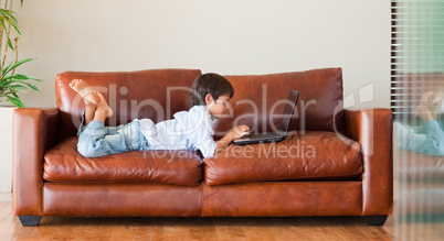 Kid playing with a laptop on the sofa