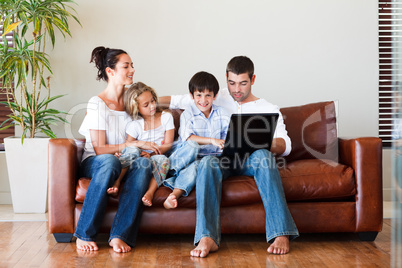 Happy family playing together with a laptop