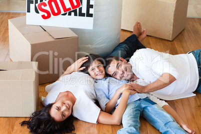 Smiling family in their new house lying on floor