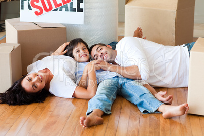Family in a new house lying on floor with boxes