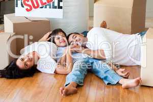 Family in a new house lying on floor with boxes
