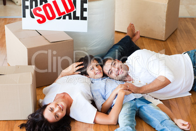 Parents and son moving house lying on floor