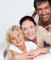 Parents and daughter on bed smiling at the camera