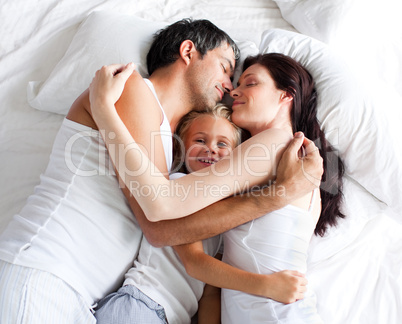Parents and daughter relaxing on bed