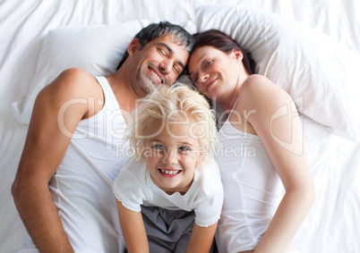 Little girl on bed with her parents smiling at the camera