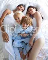 Happy parents and children together on bed