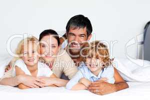 Smiling family together on bed