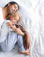 Father and daughter sleeping on bed