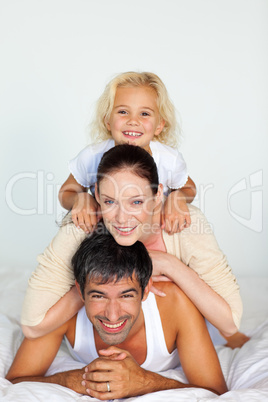 Father, mother and daughter playing in bed
