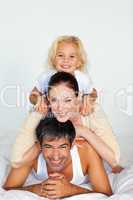 Father, mother and daughter playing in bed