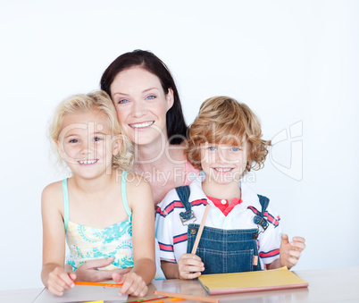 Children doing homework with their mother smiling at the camera