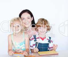 Children doing homework with their mother smiling at the camera