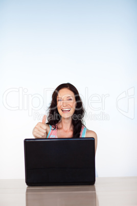 Woman using her laptop with thumbs up and copy-space