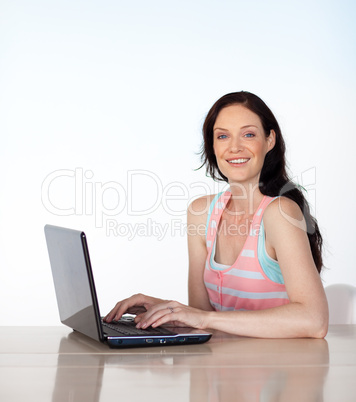 Brunette woman with laptop smiling at the camera