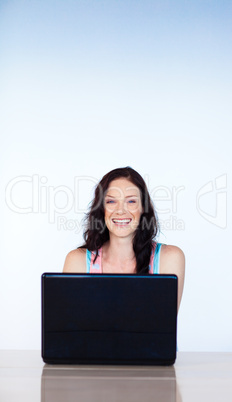 Smiling woman working with a laptop with copy-space