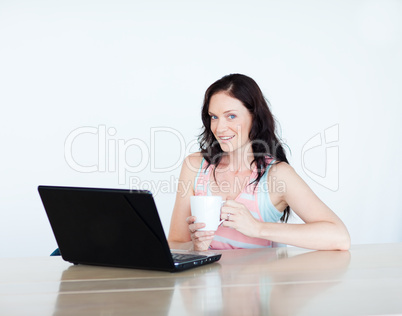 Woman using a laptop and drinking coffee