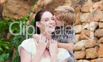 Portrait of a son kissing his mother in a park