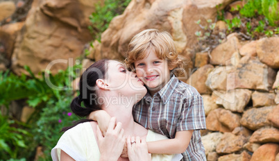 Mother kissing her son in a park
