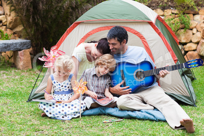 Parents and children playing a guitar in a tent