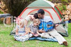 Parents and children playing a guitar in a tent