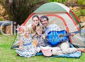 Family playing a guitar in a tent