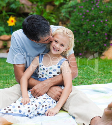Father kissing his daughter in a garden