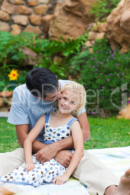 Father kissing his daughter in a park