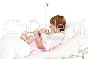 Smiling patient with newborn baby in bed