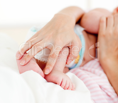 Patient's hands holding a newborn baby in bed