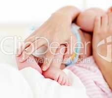 Patient's hands holding a newborn baby in bed