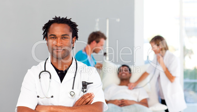 Serious doctor with folded arms and patient in the background