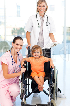 Little girl in a wheelchair doctors looking at the camera