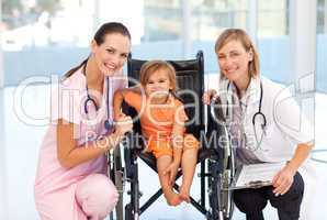 Baby in a wheelchair with nurse and doctor