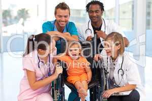 Doctors playing with a baby in a wheelchair